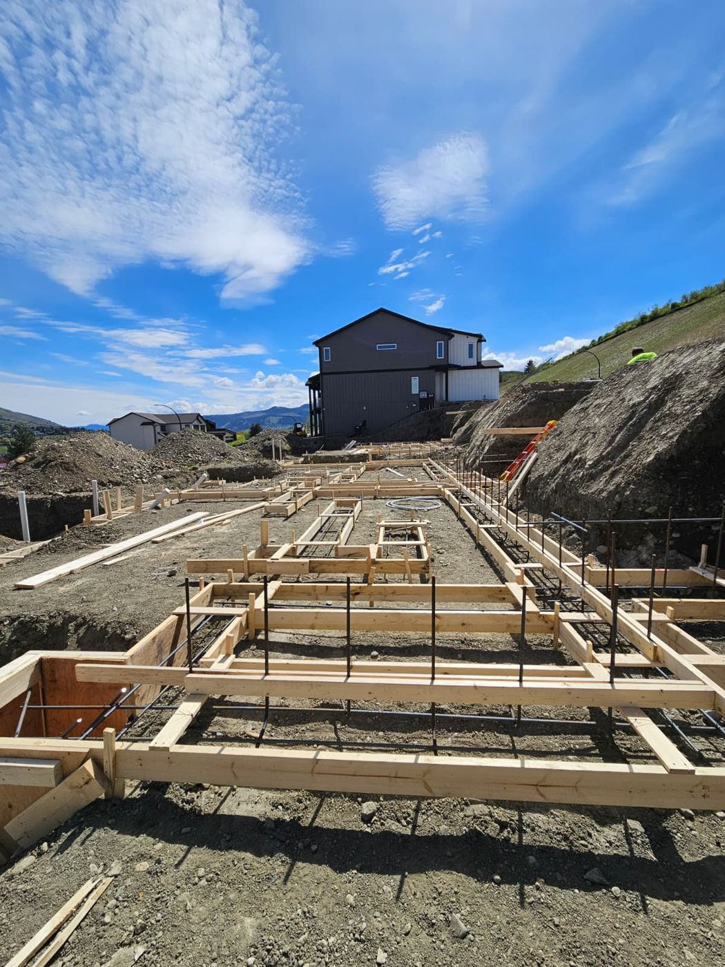 Footing forms and rebar laid out on a sloped lot ahead of framing.